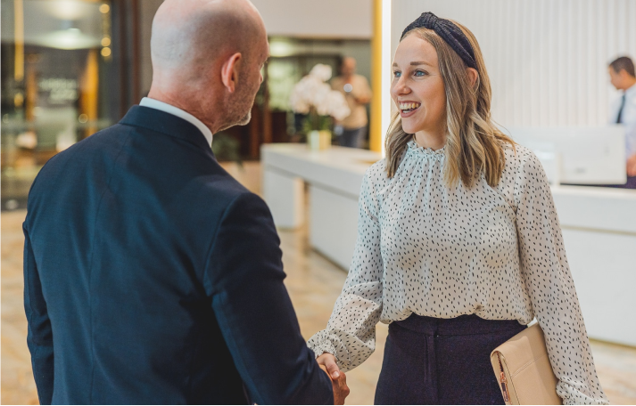 Two professionals shaking hands in an office foyer
